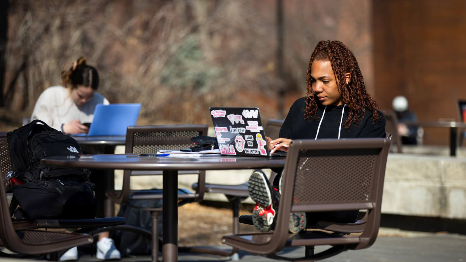 Student works on a laptop while sitting outside at a table